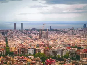 Vista panorámica de Barcelona, con la Sagrada Familia en el centro y el mar Mediterráneo al fondo, mostrando la belleza y diversidad de la ciudad