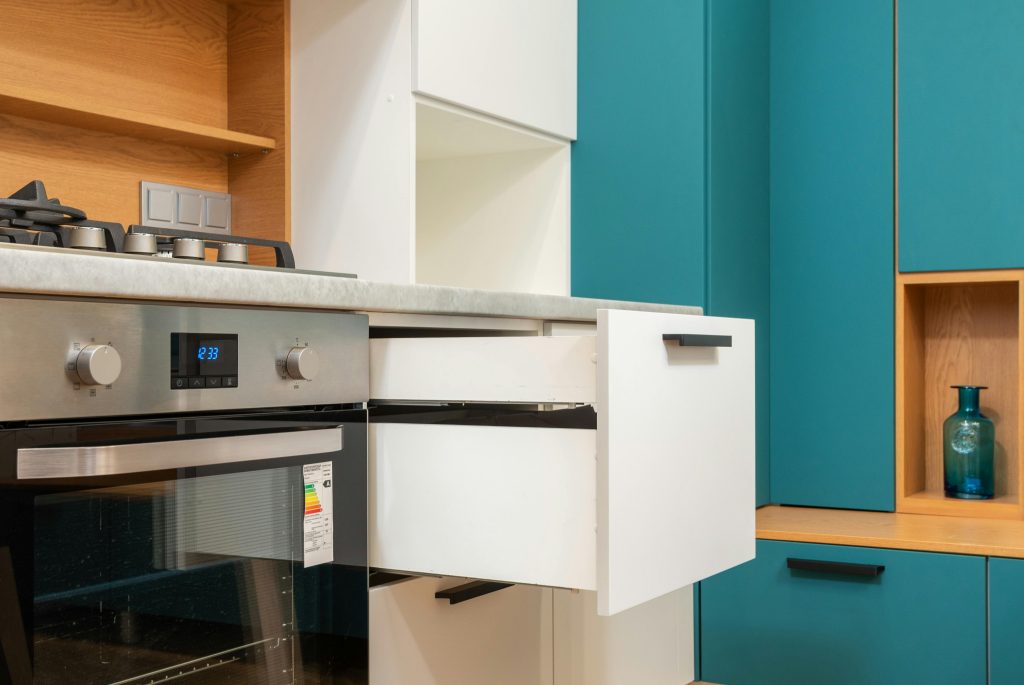 Cocina moderna con armarios azules y electrodomésticos eficientes, subrayando la relevancia de elegir electrodomésticos que ahorren energía en un piso de alquiler.