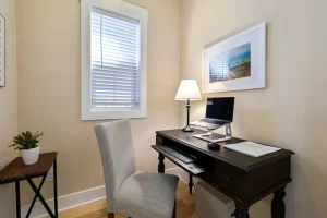 Small study corner with a dark wooden table, a grey chair, a lamp, and a laptop, showing how to organize a functional study space in a small area on a limited budget