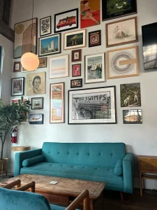 Living room decorated with a turquoise sofa and a wall full of pictures in different styles, showing how to combine diverse elements to create an eclectic and original home decor.