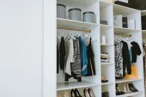 Open closet with shelves and hangers, organized with clothes, shoes, and decorative boxes, showing ideas to optimize space in a small closet