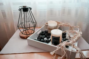 Tray with aromatic candles, decorative stones, and a designer lamp next to a rope, showing how to add cozy and warm touches to prepare the apartment for winter.