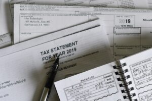 Imagen que muestra una declaración de impuestos 1099-MISC de Uber Technologies, un registro de kilometraje de negocio, y una pluma sobre papeles financieros relacionados con impuestos.