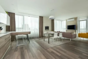 Spacious contemporary design apartment with open kitchen, dining and living area, furniture in neutral tones and large windows with curtains