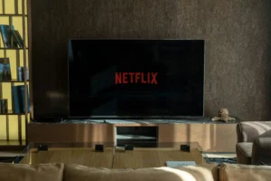Vista frontal de una televisión con el logo de Netflix en la pantalla, ubicada en un salón elegante con muebles de madera y decoración minimalista