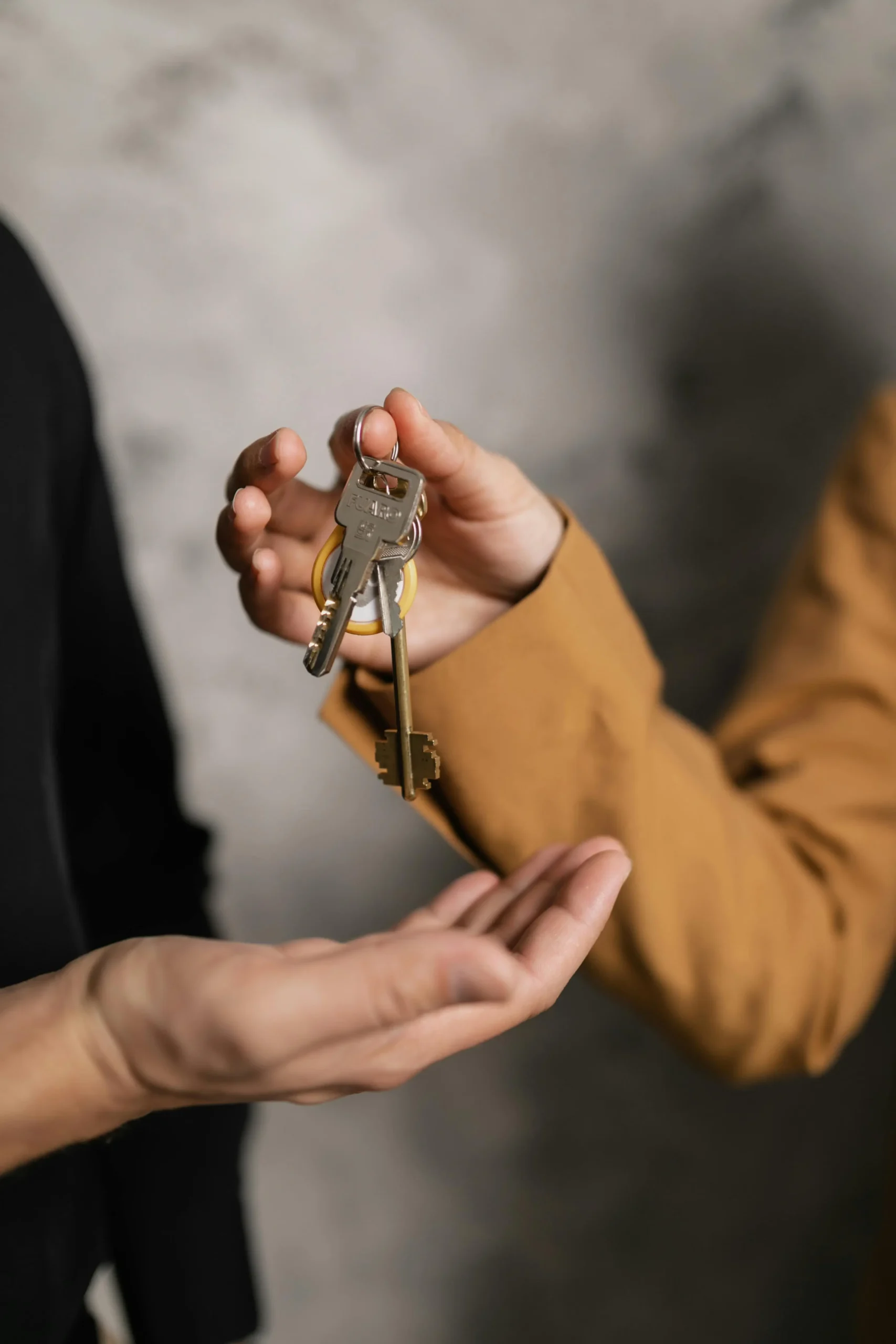 Person handing over house keys to another person