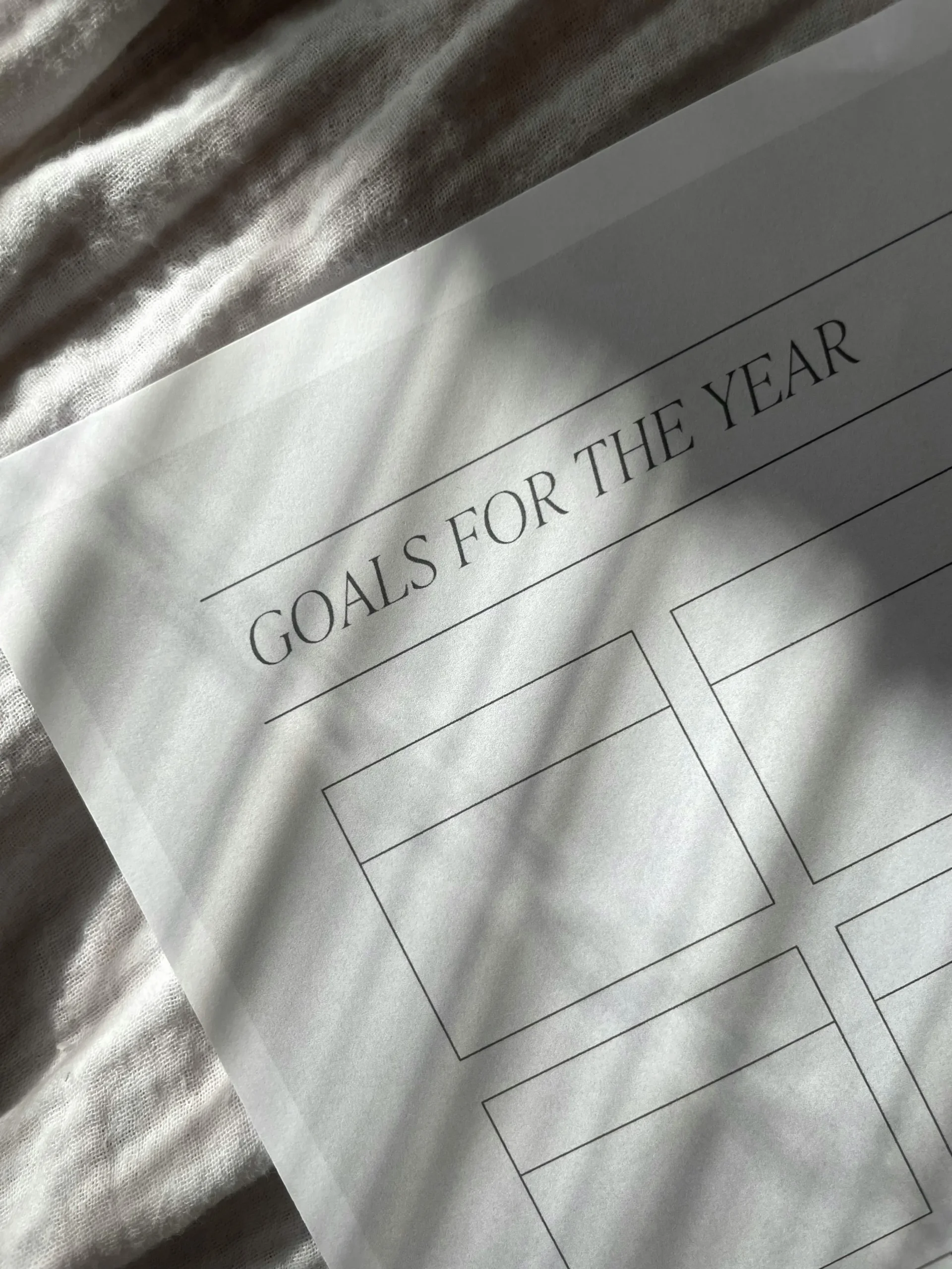 Minimalist "Goals for the Year" worksheet on a soft fabric surface with sunlight shadows
