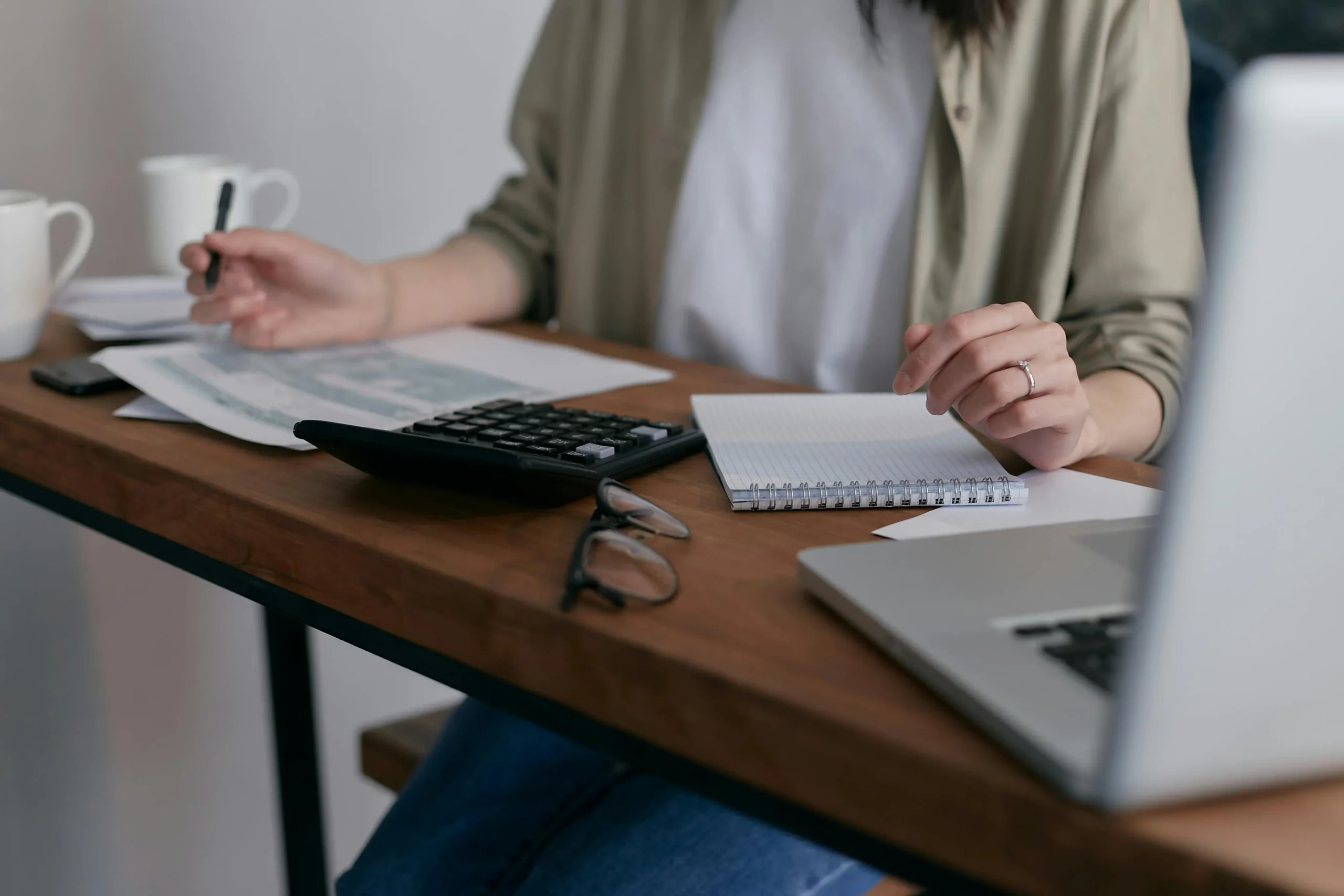 Woman working with financial documents, a calculator, and a laptop at a desk