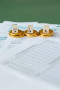 Lletres que formen la paraula “TAX” sobre monedes daurades i formularis de declaració d'impostos en paper