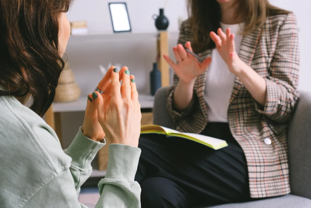Close-up of two people speaking calmly, one holding a notebook, representing communication and conflict management.