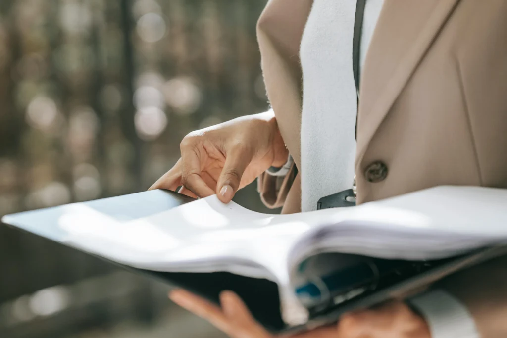 Person reviewing documents in a folder in a professional office setting, with a blurred background.