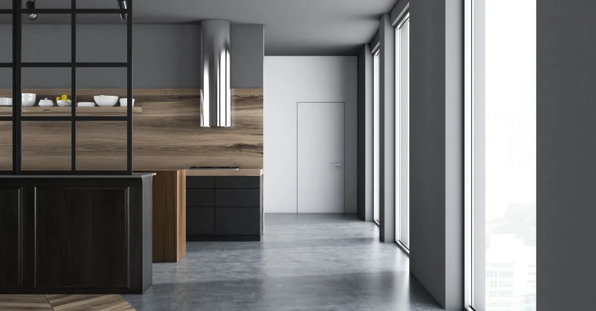 Cocina minimalista de estilo moderno con muebles negros, detalles en madera y grandes ventanales, tendencia destacada para septiembre 2025.