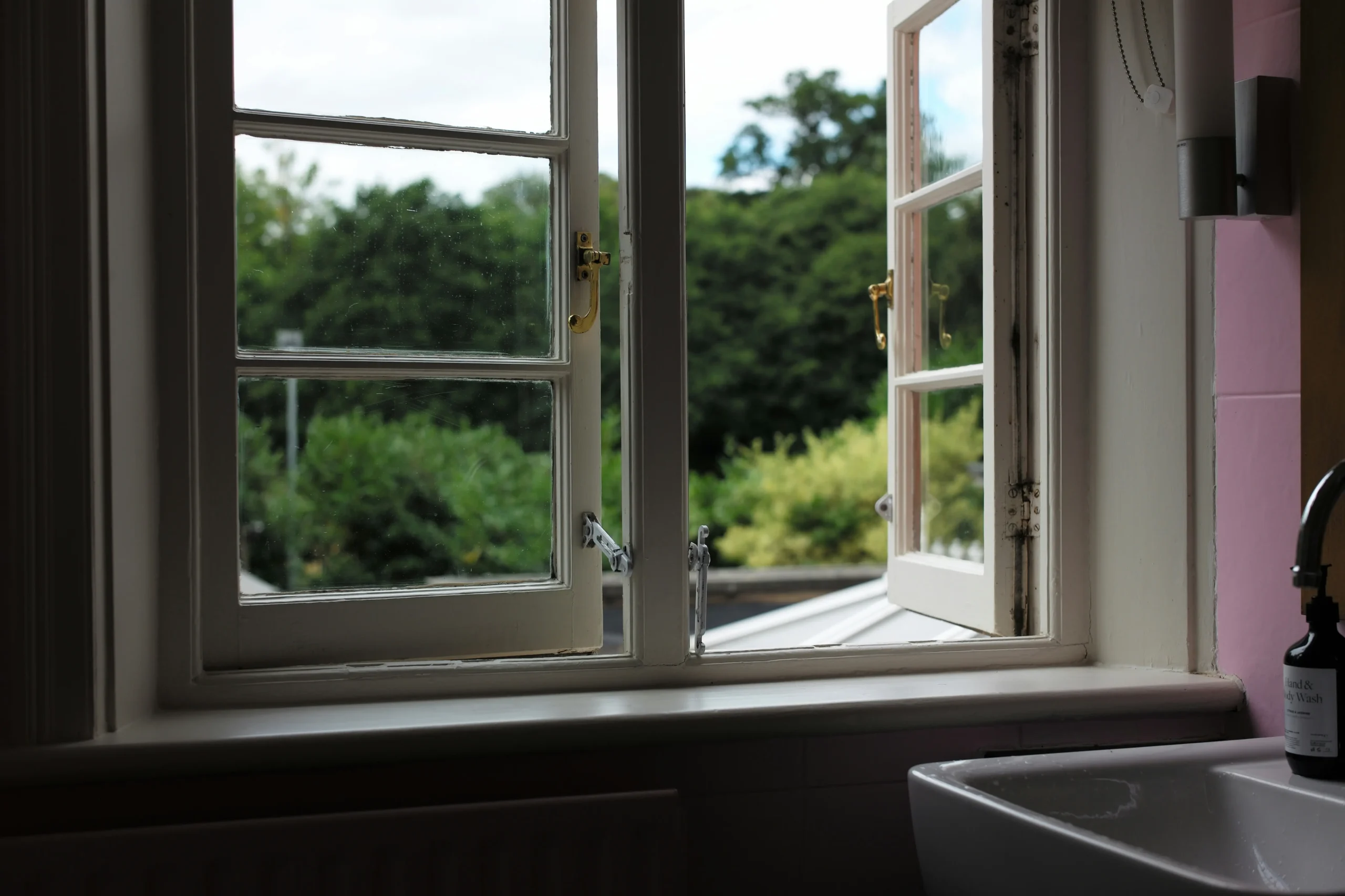 Ventana abierta con vista a árboles verdes desde el interior de una casa 