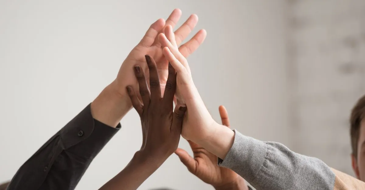 Varias manos de diferentes personas unidas en alto, simbolizando unión, colaboración y compromiso compartido en el sector turístico legal de Barcelona