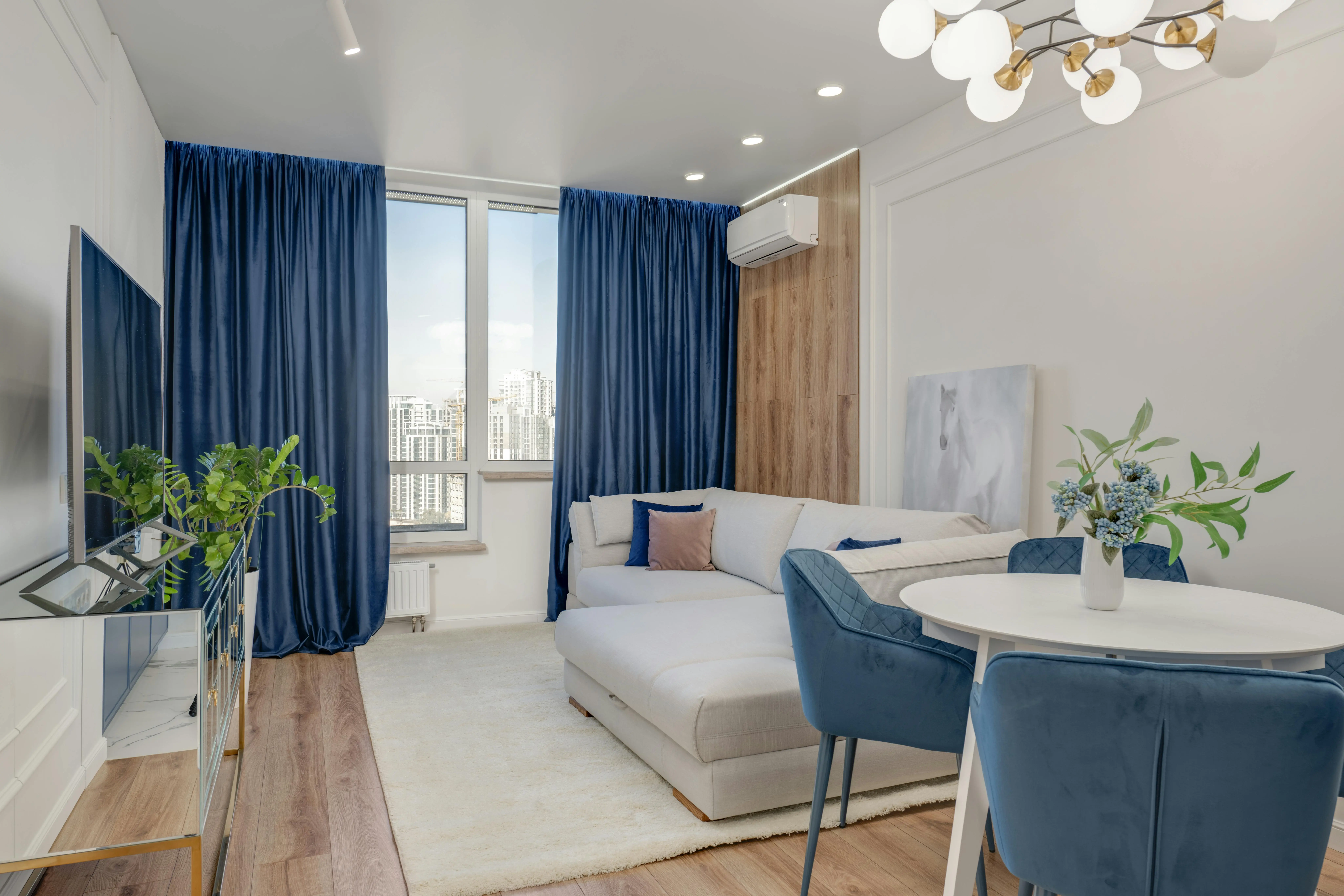 Saló lluminós amb sofà blanc, cortines blau marí i detalls decoratius, en un apartament modern de Barcelona.