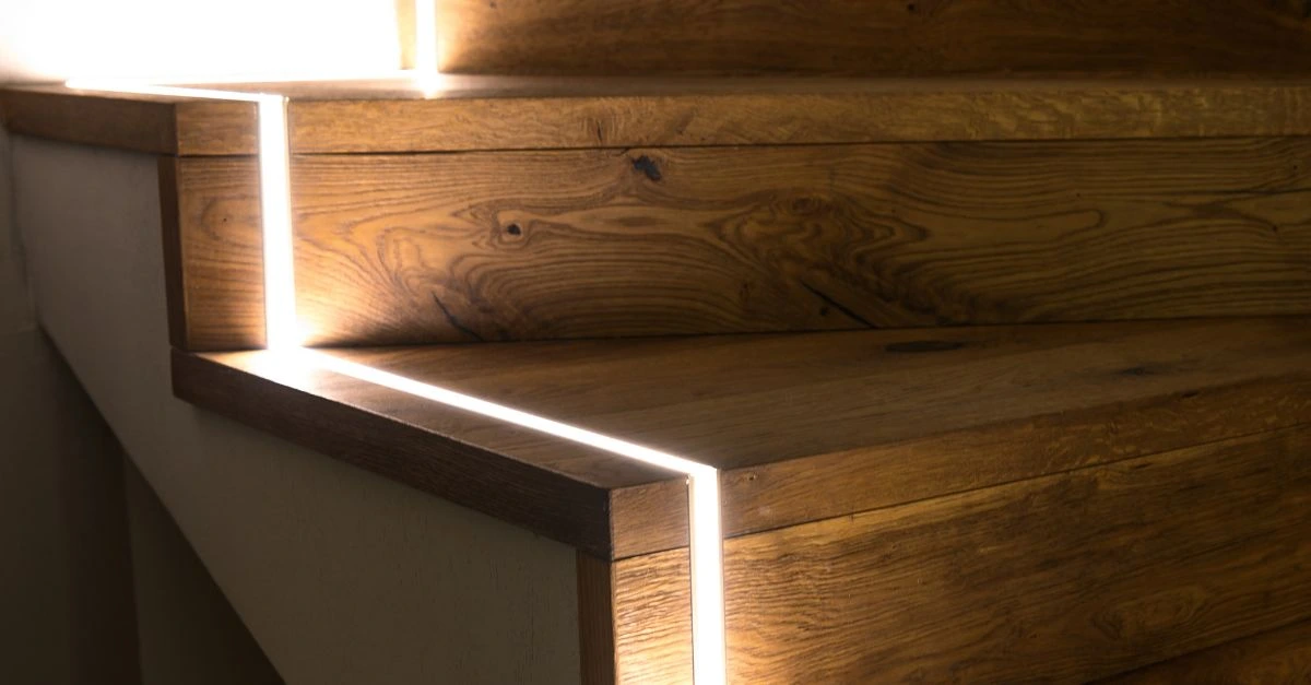 Detail of a wooden staircase with built-in LED lighting, an example of invisible technology that adds comfort and style without altering the space's design.