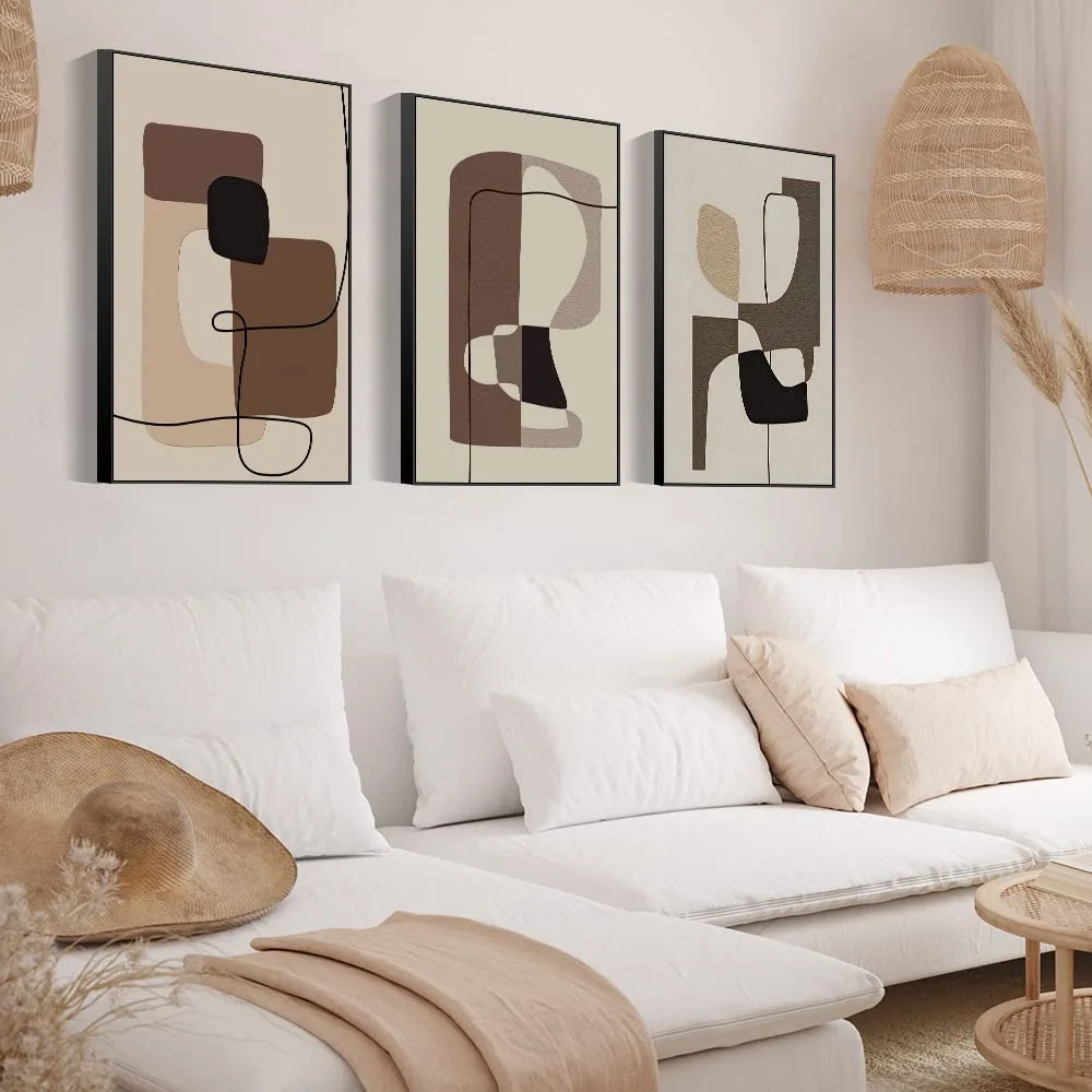 Bright living room with white sofa and wall decoration featuring three abstract artworks in beige, sand and brown tones, creating a warm and balanced atmosphere.