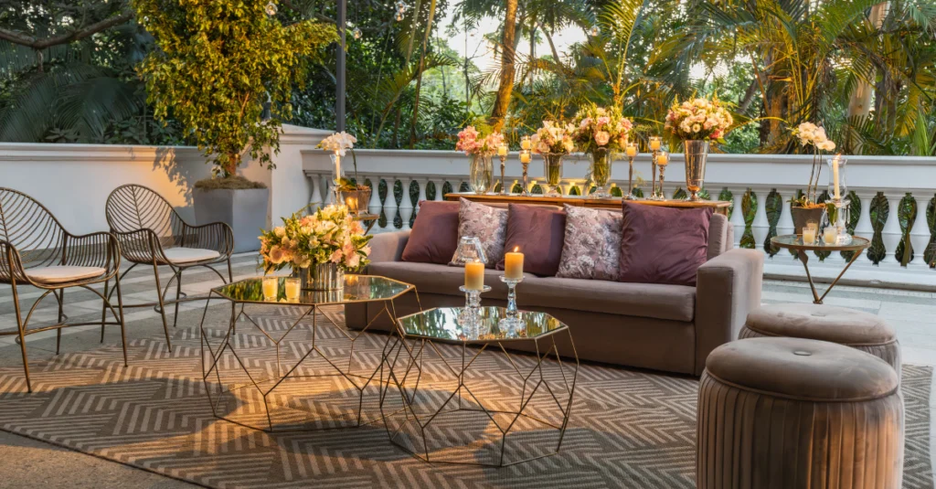 Terrassa exterior decorada amb sofà, taules auxiliars i espelmes, envoltada de vegetació, mostrant un espai cuidat i preparat per als hostes en un ambient acollidor