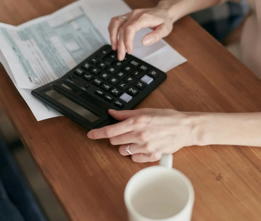 Persona utilitzant una calculadora per calcular les despeses reals i la rendibilitat d’un habitatge de lloguer.
