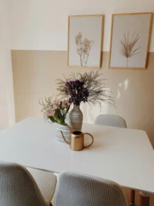 Dining area in a holiday rental with a white table, vases with flowers and minimalist decor that conveys order and a cosy atmosphere