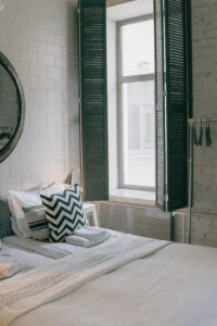 Holiday rental bedroom with a well-presented bed, natural light and decorative cushions that convey comfort and care