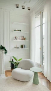 Cosy corner of a holiday rental with an armchair, natural light, shelving and elegant decor that conveys space and comfort