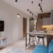Apartment interior with contemporary design, wooden kitchen with an island and cushioned stools, blue sofa, flat-screen TV, and ceiling spotlights for focused lighting