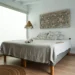 Minimalist bedroom with neutral tones and natural textures, featuring hanging wicker lamps, macramé cushions, and a wooden side table.