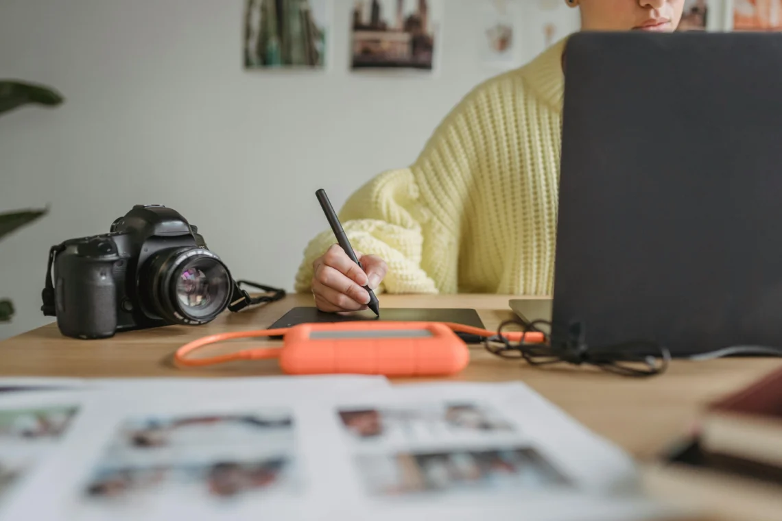 Person editing photos on a computer with a professional camera on the desk, representing the behind-the-scenes work of capturing images for a vacation rental apartment.