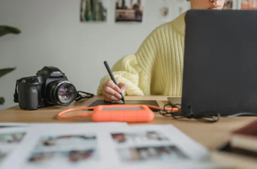 Person editing photos on a computer with a professional camera on the desk, representing the behind-the-scenes work of capturing images for a vacation rental apartment.