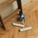 Two paint rollers and a paint can placed on a light wooden floor, ready for painting