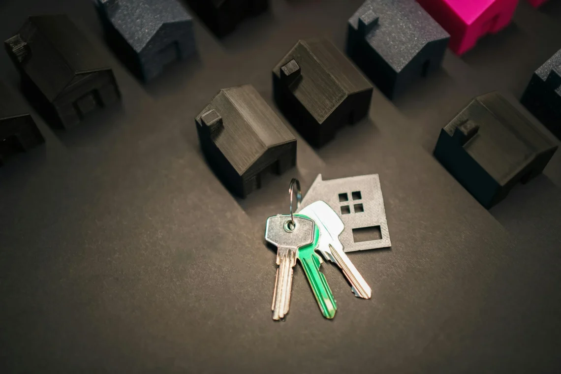 Keys on a figure of a house next to several models of houses, representing the sale or transfer of a property.