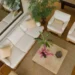 Vista aérea de una sala de estar elegante, con sofás blancos, mesas de centro de mármol, plantas decorativas y un espejo grande, todo en un ambiente cálido y acogedor.