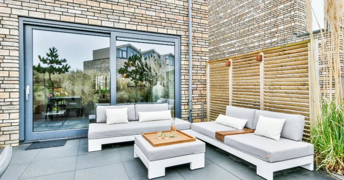 Terraza de apartamento con sofás exteriores, mesa central y decoración moderna, ideal para disfrutar en temporada alta