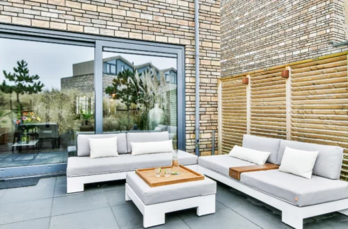 Terraza de apartamento con sofás exteriores, mesa central y decoración moderna, ideal para disfrutar en temporada alta