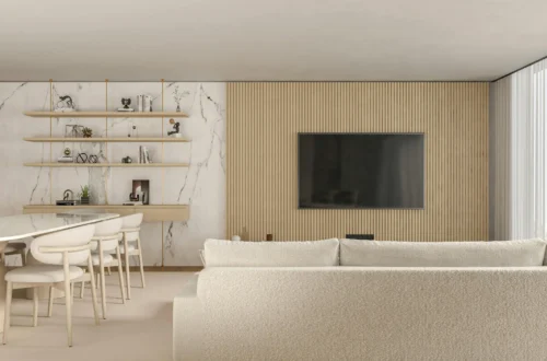 Espacio abierto de estilo contemporáneo con salón y comedor integrados, sofá en tonos claros, pared de madera con televisión, estanterías decorativas y revestimiento de mármol en un ambiente luminoso y elegante.