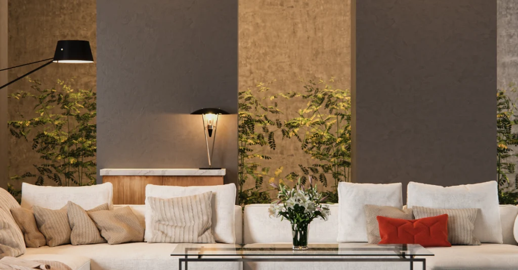 Sofà blanc decorat amb coixins de diferents tons i textures en una sala d’estar amb il·luminació càlida i plantes.